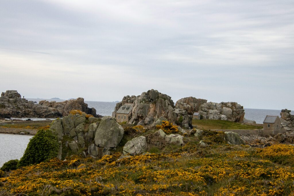 Photographie d‘un paysage marin représentant une maison près d’un bord marin, entourer de roches