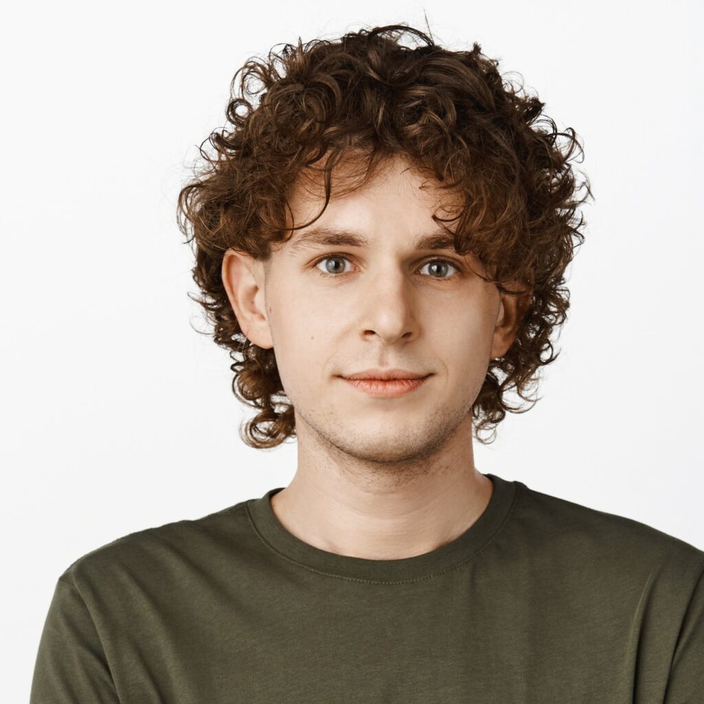 Portait photo d’un homme de face, expression faciale positive, cheveux mi-long et blouclé